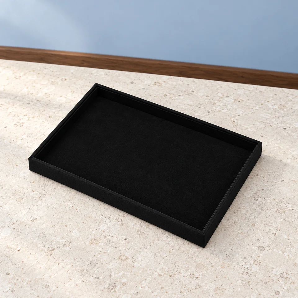 Oirlv — plateau microfibre noir de Oirlv, mise en situation dans un décor de pierre perle claire et de bleu ardoise pâle