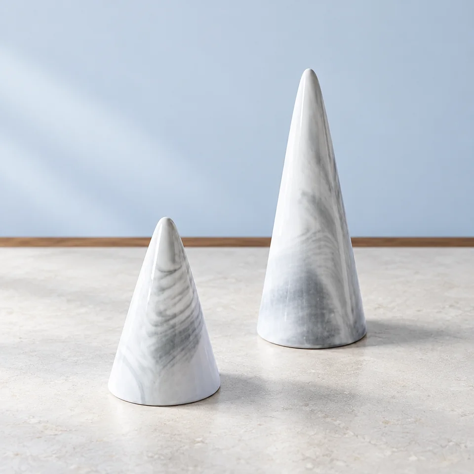 oskas — deux cônes en porcelaine marbrée grise de oskas, mise en situation dans un décor de pierre perle claire et de bleu ardoise pâle