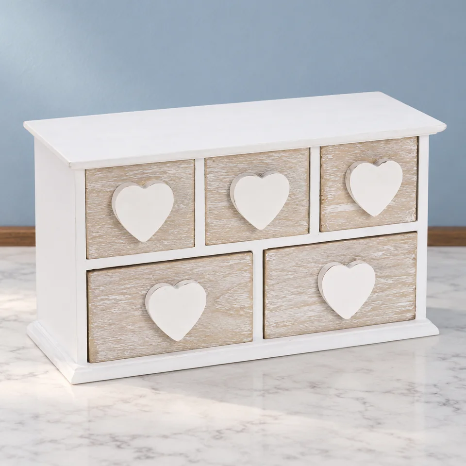 Spetebo — commode à cinq tiroirs et cœurs de Spetebo, mise en situation dans un décor de pierre perle claire et de bleu ardoise pâle